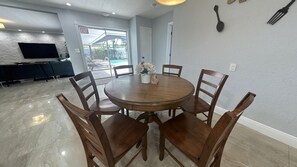 Open-concept dining and kitchen area with 6 seating dining table & 2 bar stools.