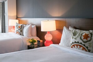 Cozy bedroom with twin beds, vibrant accent pillows, and mood lighting, perfect for a comfortable and stylish stay.