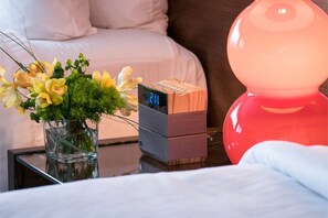 Charming bedside scene with vibrant floral arrangements and playful lampshades, adding a personal and inviting touch to your stay.