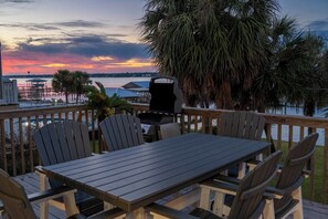Sunset patio dining with bay views and palm trees.