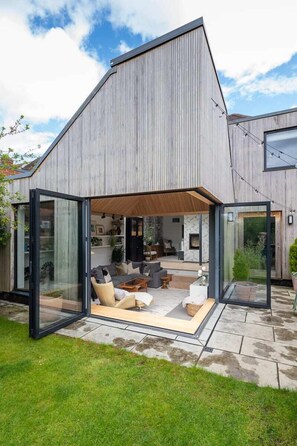 Spacious living room with expansive windows wide open, connecting effortlessly with the garden and filling the space with natural light and a fresh outdoor feel