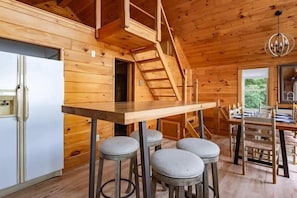 **Kitchen and Dining Area**: "Enjoy meals and gatherings in our inviting kitchen and dining area, featuring a cozy wooden interior and easy access to the loft.