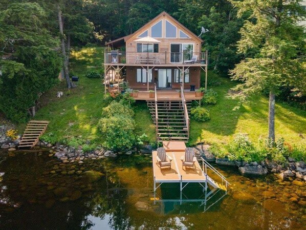 **Lakeside House with Private Dock**: "Relax in comfort at our beautiful lakeside house, featuring a private dock and outdoor seating for the perfect waterfront experience.