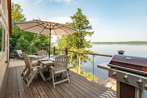 **Deck with Umbrella and Grill**: "Dine al fresco on our spacious deck, complete with a large umbrella, comfortable seating, and a grill – all with a stunning lake view.