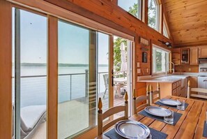 **Dining Area with Lake View**: "Dine with a view in our cozy dining area, featuring large windows and doors that open directly to the deck overlooking the tranquil lake.