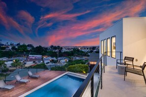 Cascading from the second-floor balcony, the pool gleams like a sapphire jewel amidst lush greenery. Its pristine waters reflect the sky, offering a panoramic view of the area.
