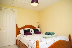White patterned duvet cover on a double bed with cushions, throws, and neatly folded towels