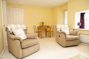 2x Armchairs with cushions and dining table behind to seat 2