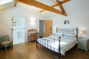 King size bedroom with door to en suite wet room, bed, drawers, lamps, chair and wash stand