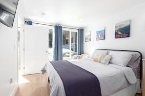 Bedroom with queen bed, tv, and lots of windows