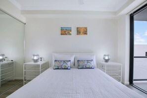 The primary bedroom has a cosy queen-sized bed that adjoins a sunlit balcony. 