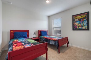 Vibrant kids' room with twin superhero beds, cozy carpet, and comic wall art.