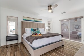 Primary bedroom featuring a King  bed, smart TV, en-suite bathroom, walk-in closet, and a patio that leads to the side of the house.
