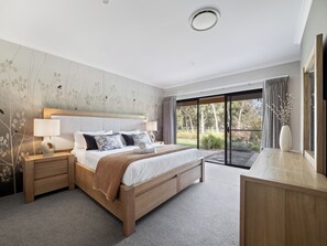 The primary bedroom is a peaceful sanctuary with a king bed, elegant décor, and sliding doors leading to a private garden deck.