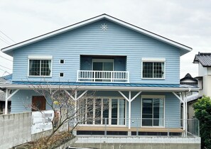It features a covered porch reminiscent of the American West Coast and a large window leading to the deck.