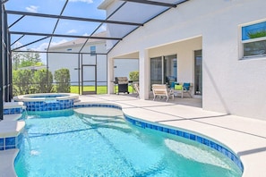 Private screened-in back patio with swimming pool and spill-over hot tub.
