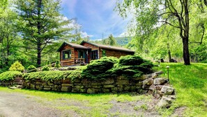 Spring view of Grandview Cabin with rock walls and trees.