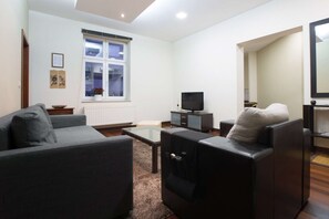 Living room with double sofa bed, TV and entrance to the dining area and kitchen.