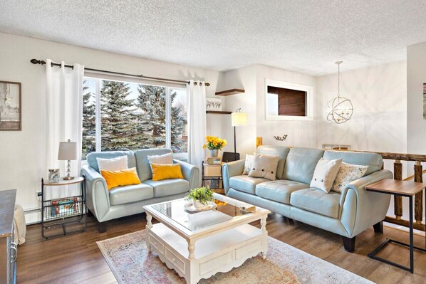 The living area has new furnishings, a gas fireplace, and views of trees