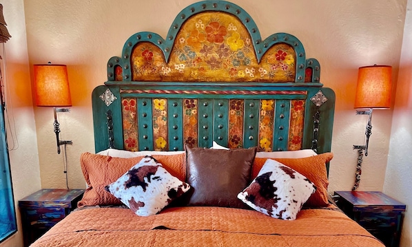 King-size bed with vibrant textiles and artistic accents.