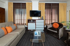 Contemporary Junior Suite showcasing a king bed, sleek media setup, and a comfortable sofa bed for extra guests.