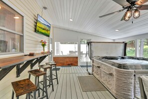 Hot tub,seating, and smart TV in screened porch.