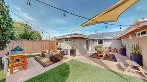 High-end patio furniture, a private gas grill, and a separate alfresco dining area under ambient string lights