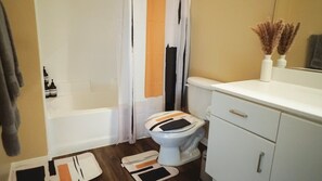 Bathroom essentials: Bathtub, blowdryer, toothpaste, towels, lotion, shampoo, body wash, conditioner, and hand soap.
