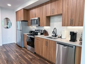 Fully equipped kitchen designed for extended stays, featuring a stovetop, microwave, refrigerator with freezer, blender, coffee machine, and complete dinnerware.