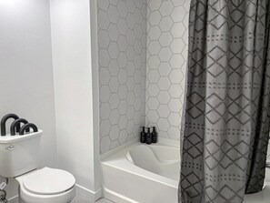Bathtub, bidet, blowdryer, toothpaste, towels, lotion, shampoo, body wash, conditioner, hand soap
