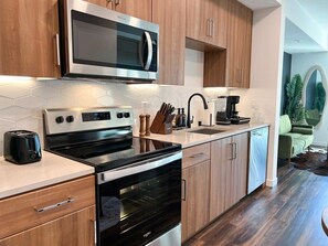 Modern kitchen amenities for extended stays: stovetop, fridge, dishwasher, microwave, kettle, toaster, blender, and a full knife set.