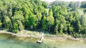 OVERALL:  An aerial photo from out over the lake showing the private lakefront, dock, kayaks, and canoe with the house in the background.