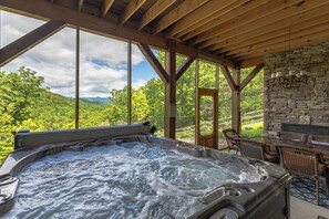 Lower level screened-in porch with outdoor dining for 6, hot tub, and access to the backyard with traditional fire pit. Please note: this fireplace is NOT operational.
