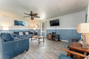Lounge with loved ones in the coastal-themed living room, which has cozy seating for six around a mounted high-resolution flat-screen TV. 