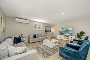 The spacious living area comfortably seats a large group, with a centrally positioned large high-definition TV for optimal viewing. It offers excellent ventilation and efficient air conditioning, ideal for relaxation and leisure.