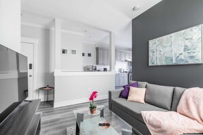 Bright Kitchen With Modern Cabinetry, Stainless Steel Appliances, And A Glass Dining Table