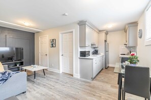Bright And Open Living Area Featuring A Smart TV And A Fully Equipped Modern Kitchen