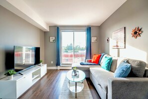 Spacious Living Area Featuring A Comfortable Sofa Bed, A Smart TV, And Access To A Bright Balcony