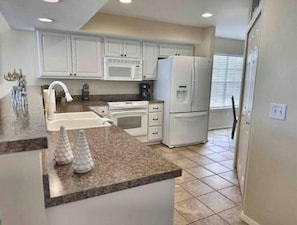 Large and well stocked kitchen with bar open to living area on one side.
