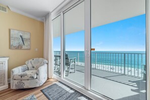 Floor-to-ceiling glass sliders open out to balcony with pristine beach views