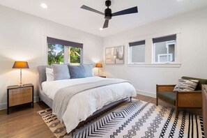 The primary bedroom equipped with a king bed, TV and an extra chair. An en suite bathroom is accessible as well.