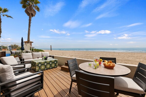 Toes in the sand! Deck with comfortable couch, chairs, and dining area.