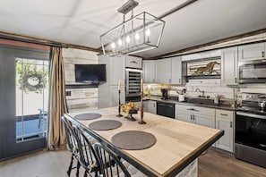 Modern kitchen featuring a rustic charm with weathered wood accents and sleek white cabinetry, complete with a spacious island and state-of-the-art appliances, ideal for culinary enthusiasts.