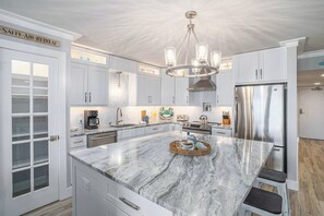 Well lit kitchen that's fully stocked with all the cooking supplies you need to prepare a meal . Also has a separate pantry and large island.