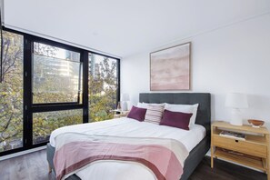 The light-filled bedroom highlights a queen-sized bed, set with side tables and reading lights.

