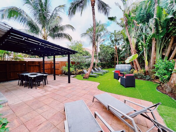 The Backyard

A large backyard full of Lucious greenery all around. The backyard has an outdoor table for all guests, 6 lounge chairs to soak in the sun, a fire place, and an above the ground pool to stay cool year around.
