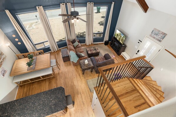 View of the living and dining space from the upstairs loft w/ vaulted ceilings. 