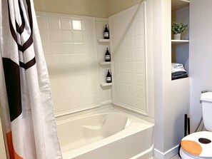 Bathroom equipped with a bathtub, bidet, hairdryer, toothpaste, towels, and complimentary amenities including lotion, shampoo, body wash, conditioner, and hand soap.