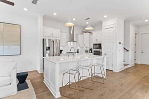 A fully equipped kitchen with high-end appliances, stylish bar stools, and elegant pendant lighting for a sophisticated cooking experience.