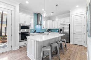 Open kitchen with stainless-steel appliances, and island seating for 4